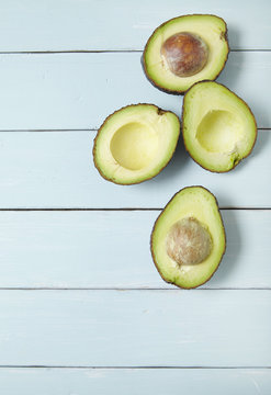 Halved avocados on a painted wooden kitchen counter background