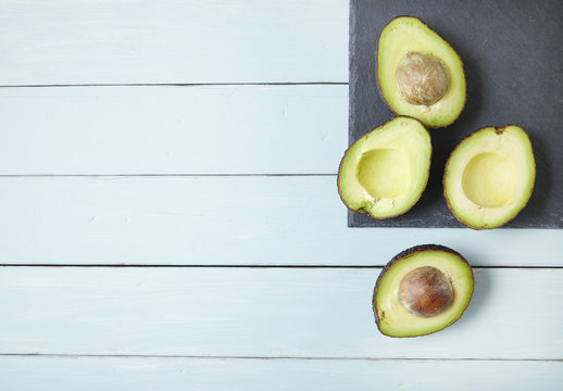 Halved avocados on a painted wooden counter top background