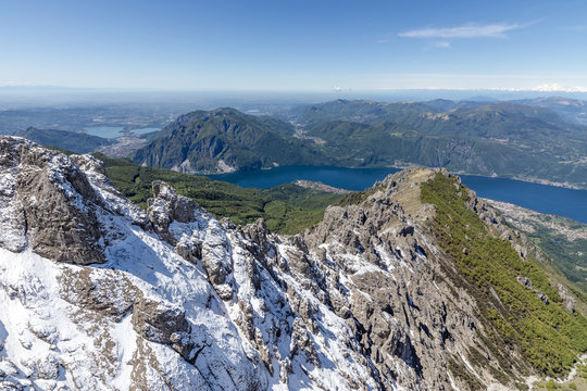 Aerial view of the snowy ridges of the Grignetta mountain with Lake Como in the background, Lecco Province, Lombardy