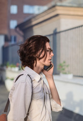 Handsome young man talking on smartphone in the city, in front of modern building.