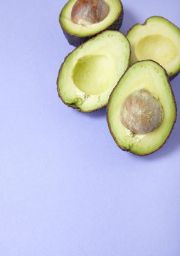Avocado halves arranged on a purple background to form a page border