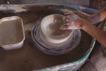 Mid section of female potter making pot
