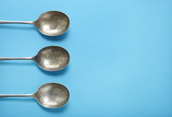 Silver dessert spoons on a blue background forming a page border
