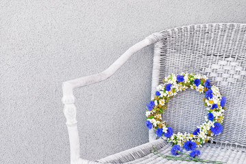 Bluet floral wreath in a wicker chair.