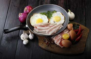fried eggs with vegetables on wooden background