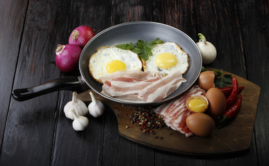 fried eggs with vegetables on wooden background