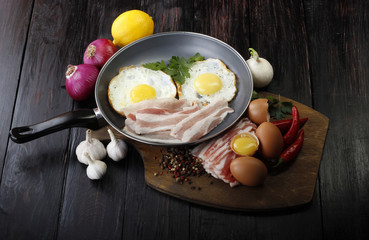 fried eggs with vegetables on wooden background