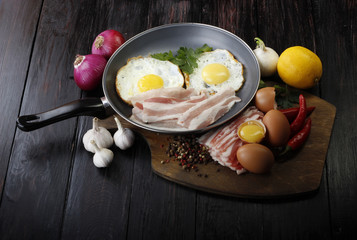 fried eggs with vegetables on wooden background