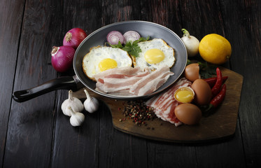 fried eggs with vegetables on wooden background
