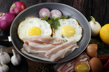 fried eggs with vegetables on wooden background