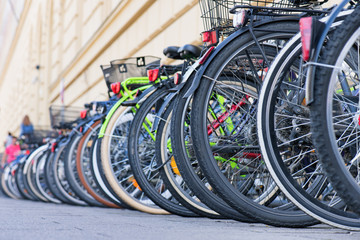 Group of bicycles in the row on sidewalk. Selective focus. Parking for bikes in big European city. Close up of wheel.