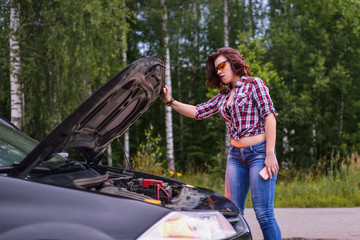 Woman and broken car with opened hood