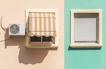 two windows one with air conditioner of a colorful facade in a residential building orange and green pastel