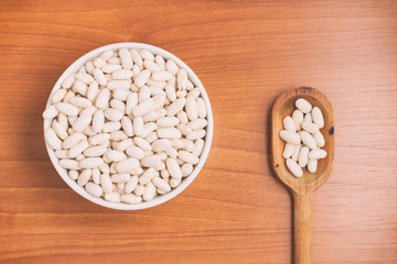  White beans into a bowl and spoon over a wooden table. Phaseolu