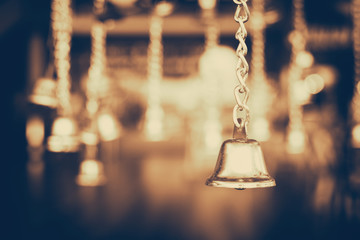 Golden jingle bells hanging in the dark background with vintage filter