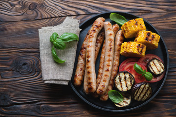 Frying pan with grilled sausages and vegetables, high angle view