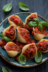 Closeup of baked conchiglioni with mincemeat and tomato sauce