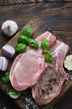 Above view of raw fresh pork chop steaks with seasonings