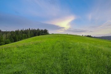 Mountain slope with green grass against the sky