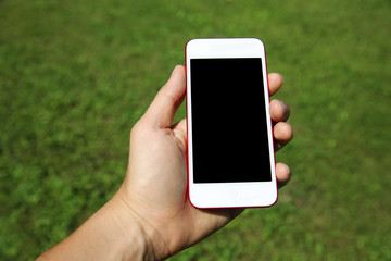 Hand holding smartphone against green background