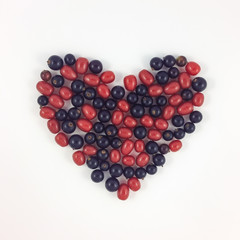 Heart shape made of currant and gumi berries on white background
