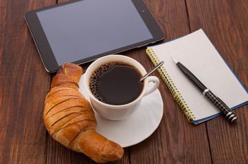 breakfast with cup of black coffee, croissants and notebook