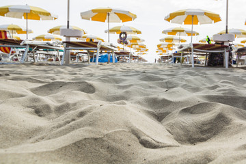 the foreground of a beach with umbrellas in the background.