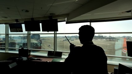 In airport air traffic controller is looking into distance holding radio