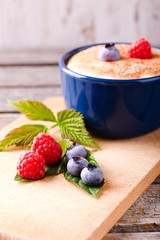 Blue and red berries on green leaves and chopping board