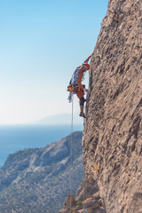 The climber climbs the rock against the sea