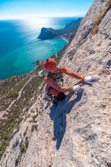 The climber climbs the rock against the sea