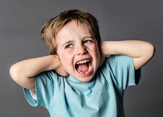screaming young boy suffering from domestic pain covering his ears