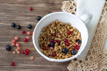 Homemade delicious healthy granola with nuts, seeds, honey and fresh berries in a ceramic cup