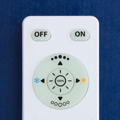 White remote control with the buttons on the blue background