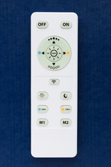 White remote control with the buttons on the blue background