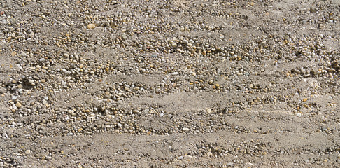 Grobe Betonwand mit teilweise freiliegenden Kieselsteinen 