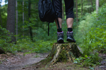 Girl standing on a tree stump, hiking boots in focus