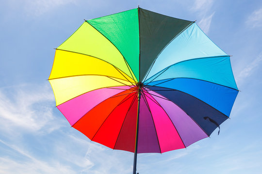 open colorful rainbow umbrella on blue sky background