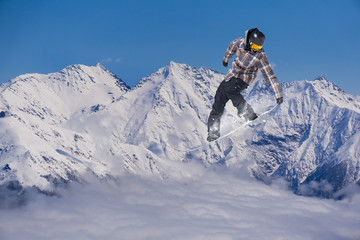 Snowboarder jumps on winter mountain.