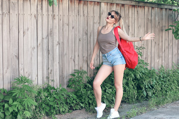 Fototapeta na wymiar A dancing girl wearing glasses, denim shorts, gray shirt with backpack