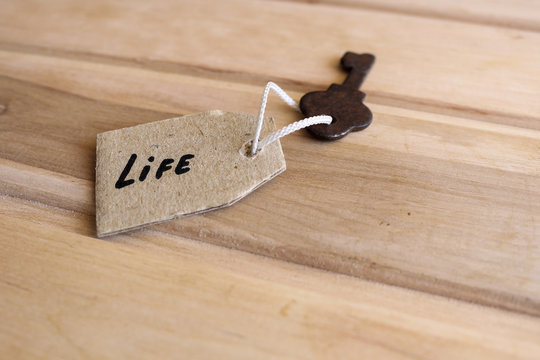 The concept of a happy life - the old key with a tag on wooden background.