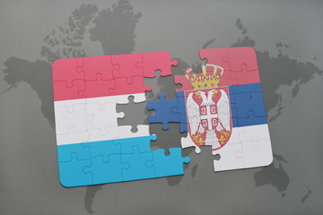 puzzle with the national flag of luxembourg and serbia on a world map background.