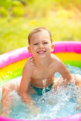 Little boy in inflatable swimming pool outdoor, having fun