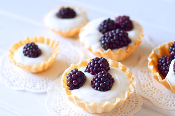 Tartlet with cream an fresh dewberries. Sweet berry summer desse