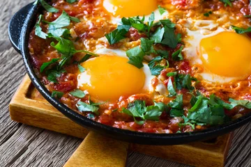 Abwaschbare Fototapete Egg dish with tomato sauce  served in  cast iron pan, shakshouka © istetiana