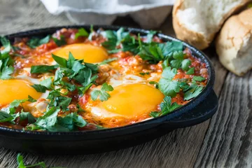 Crédence de cuisine en verre imprimé Oeufs sur le plat Egg dish with tomato sauce  served in  cast iron pan, shakshouka