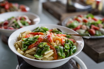 Bruch buffet with various salads with  pasta  vegetables salad at the foreground . Close up on a macaroni salad with tomatoes and green pepper