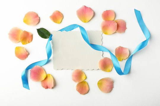 Rose petals, ribbon and card on white background