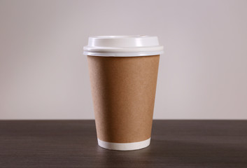 Paper cup of coffee on light background