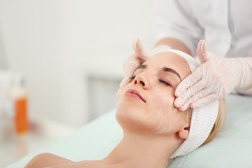 Cosmetologist applying cream on female face